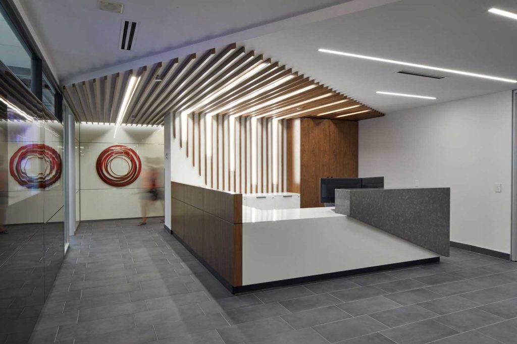A reception area with gray slate flooring, and a wood slatted pattern on the wall and ceiling.