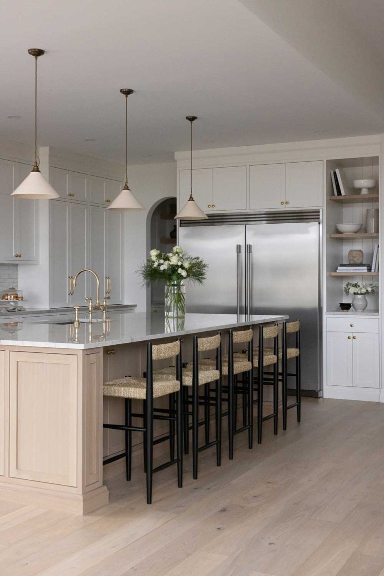 Large island and a huge stainless steel double door fridge are the centerpieces in this kitchen