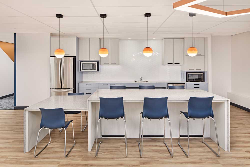 Kitchen area with large island and seating and accent orange pendants above