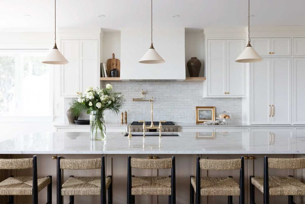 Stunning view of the kitchen looking onto the huge kitchen island and the wall with stove and hood and wall cabinetry