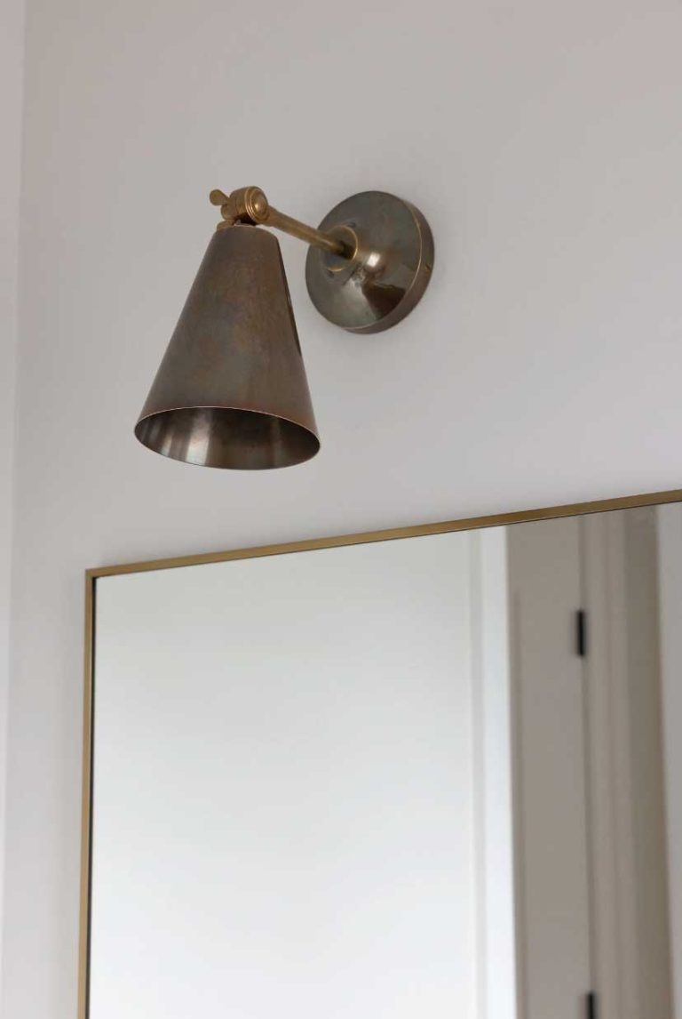 Unlacquered brass wall sconces in powder room are developing a natural patina