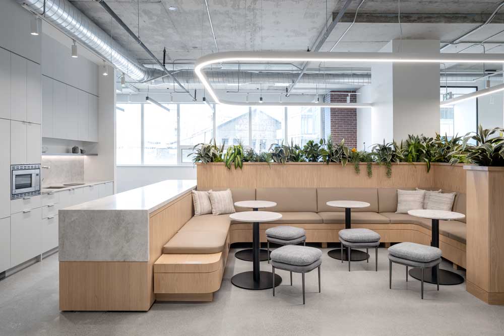 Kitchen and cafe hub with a simple neutral colour pallete with natural materials and finishes throughout, modern overhead lighting, and biophilic details