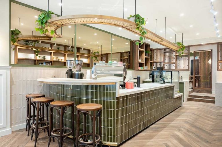 View of the cafe counter area from the entrance, greenery and live plants, green and wooden finishes all reminiscent of nature
