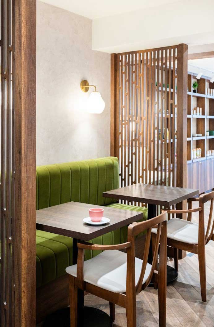 wooden and invigorating green furniture and perforated wood panels create inviting nooks for customers to savour their coffee