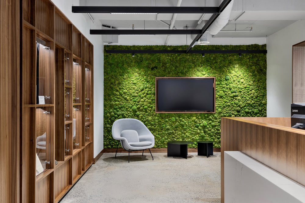 The reception area has a large biophilic wall with a large TV screen on it