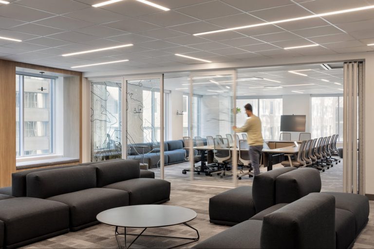 The large conference room is behind moveable sliding glass doors with a topographic map graphic, is adjacent to the lounge area with black comfortable sectional seating