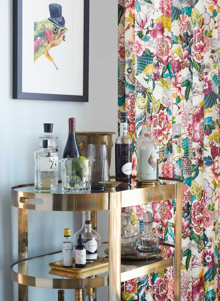 A golden bar cart against the colourful drapery in the living room