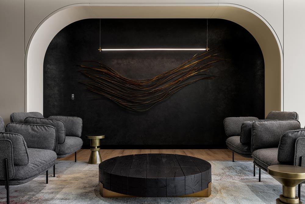 Lounge seating area flexible furniture. A black feature wall with detail and modern minimalist linear lighting above