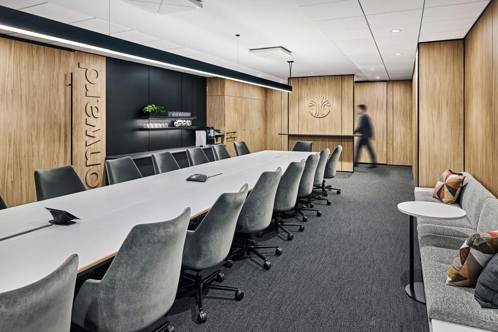 A large conference room with walls covered in light wood finish and neutral coloured furniture
