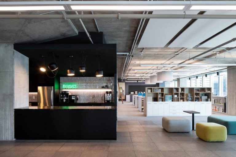 Cafe area with flexible modular furniture pieces and the work stations visible behind the large shelf separating the two areas