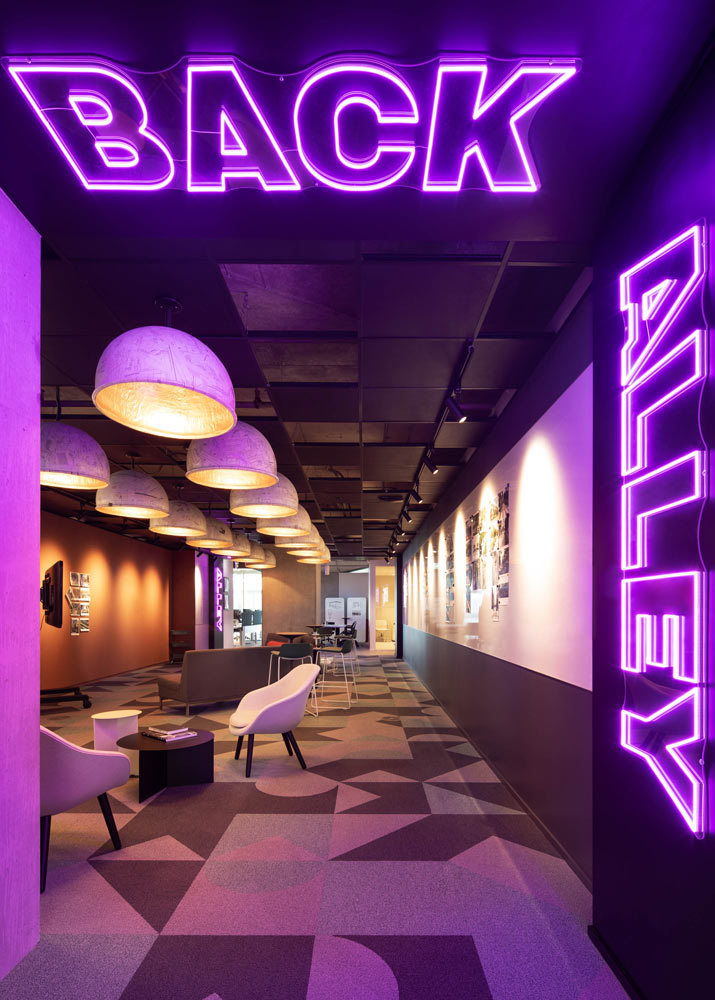 Back Alley acts as a casual, collaborative hub with a relaxed atmosphere, with casual seating and neon lighting in combination with pendant lighting, and geometric patterned flooring