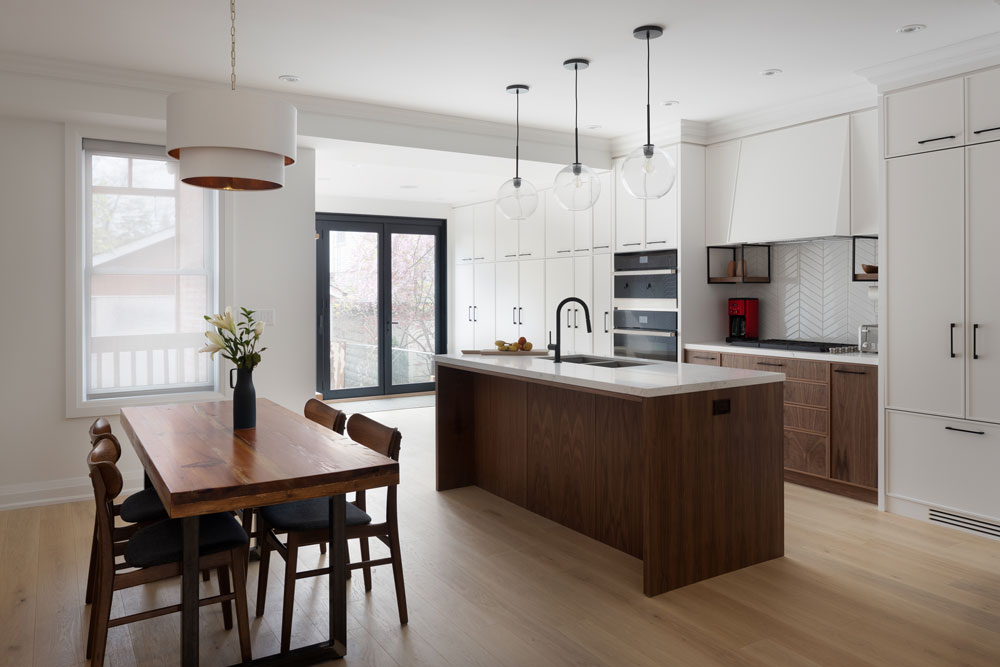 Kitchen and dining area in a white and wood combination finishes. The dining table and chairs is modern century inspired with accent lighting above