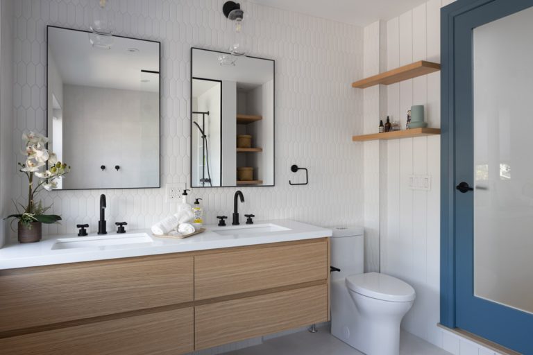 Ensuite bathroom in wood finish with industrial style mirrors and lighting and hardware in black colour, stained glass door with blue coloured frame