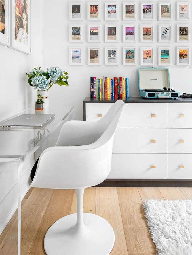 One of the kids' rooms in predominantly white colour scheme with colourful music inspired art on the walls, a record player and a retro looking chair and table