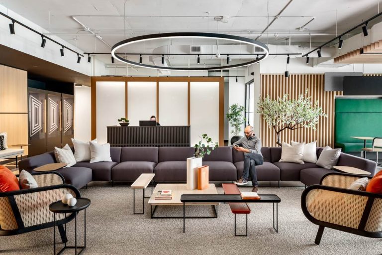 Reception area complete with a large sofa and bamboo chairs, large circular light above, and clean lines and contrasting colours. The reception desk is visible behind the sofa against the Japanse inspired paper and wood wall