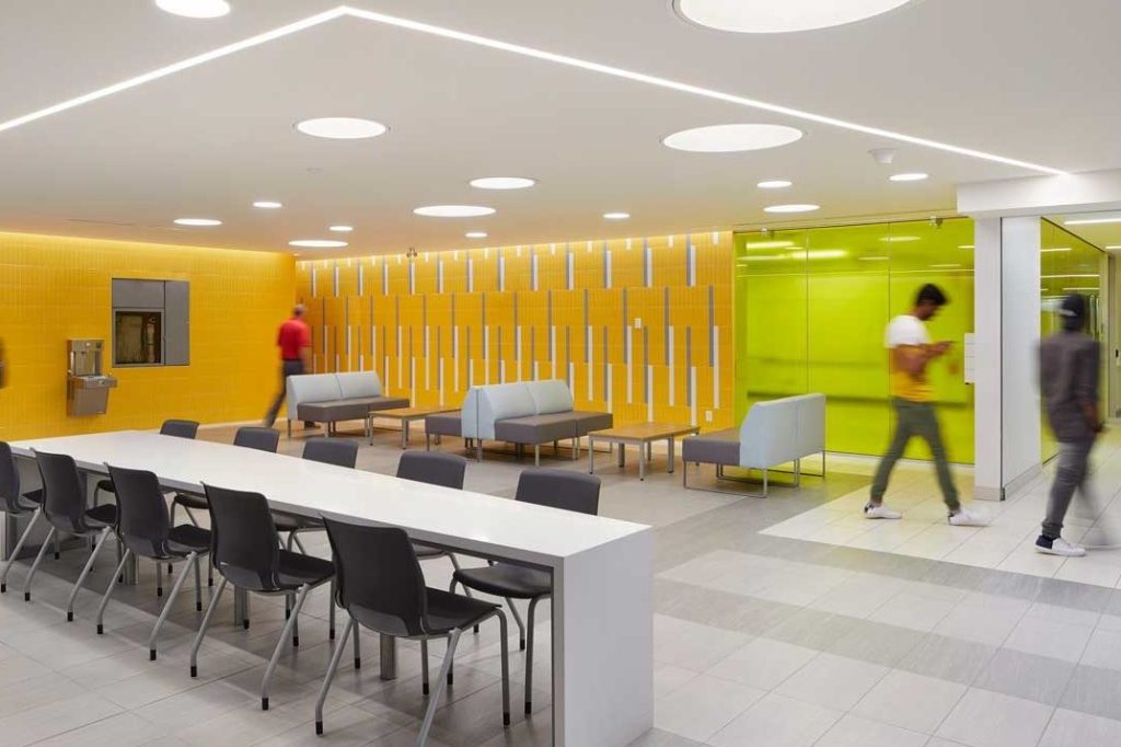 Students pass through a study space lined in bright tangerine at Fleming College.