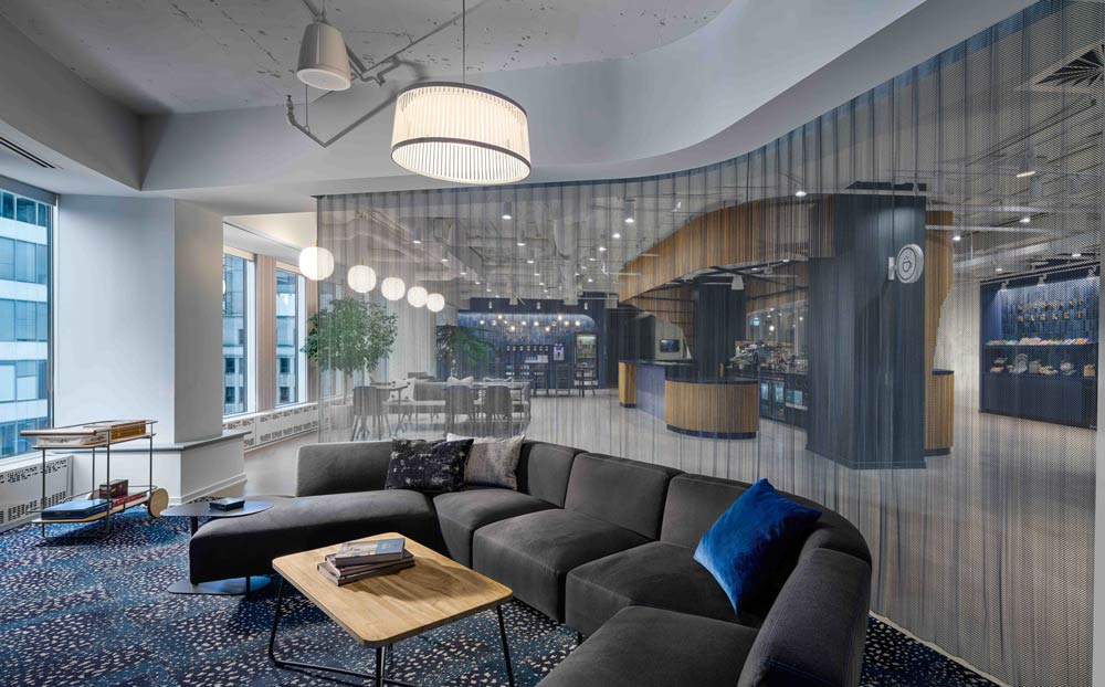 Evening Lounge-The seating area next to the coffee shop, displaying dark grey furniture in combination with dark blue details throughout, from cushions to wall colour on the opposite side. The seating area is separated from the rest of the space with a see-through draped fabric for privacy