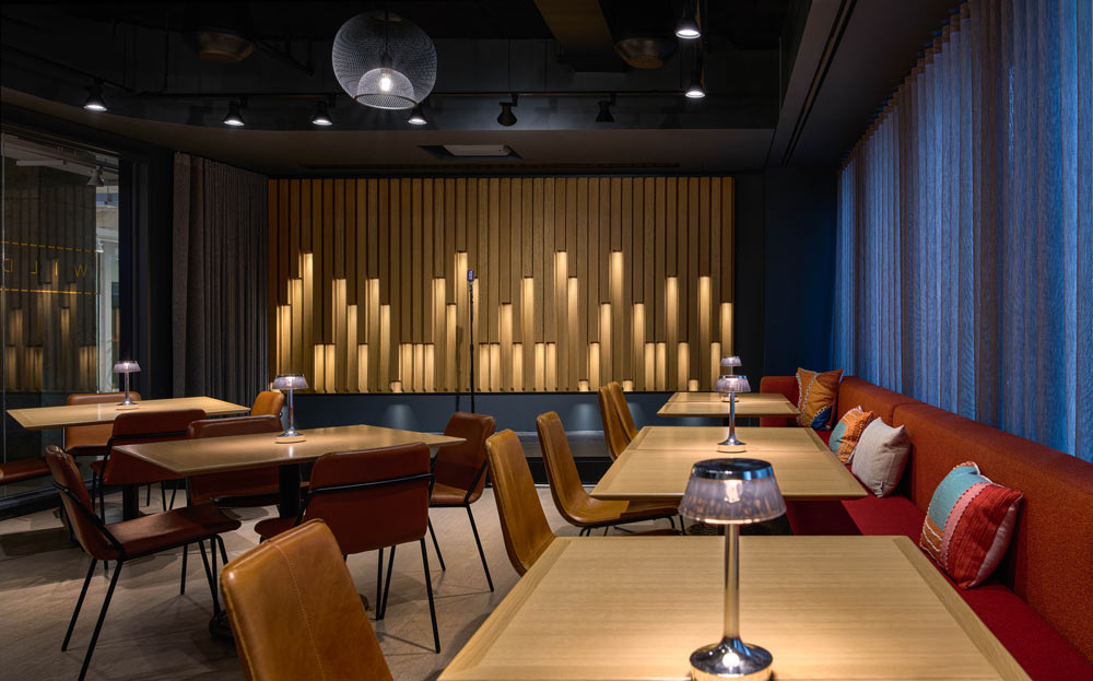 A dark and cozy interior of the karaoke lounge with a lot of wood details, dark walls and dark red and leather seating. A very moody vibe