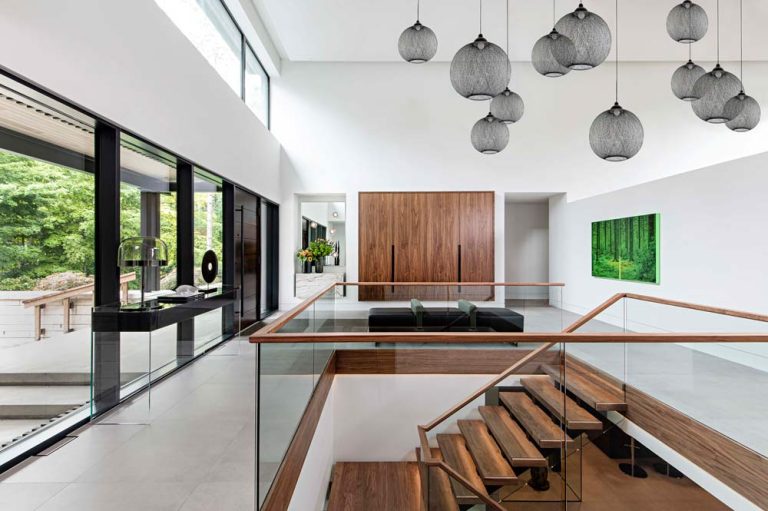 Entrance to the house is clean and modern, predominantly white walls and stunning chandelier made of multiple black mesh balls that hangs above the wooden staircase to the basement area.