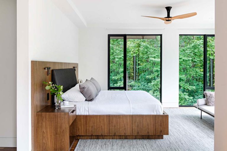 Principal bedroom featuring a wooden framed bed and modern floor to ceiling windows with modern black frames