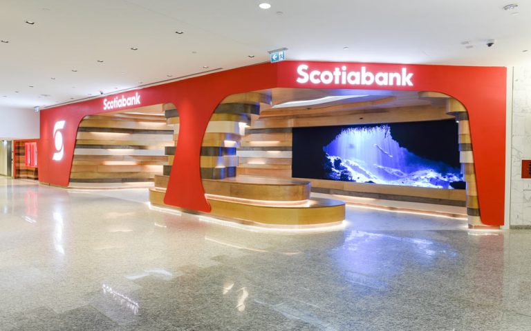 View of the entire Scotiabank North Concourse Lounge, with red framing all around branded wit the logo and inside are the organic occupiable space of undulating wood striations akin to natural cave formations seen in nature