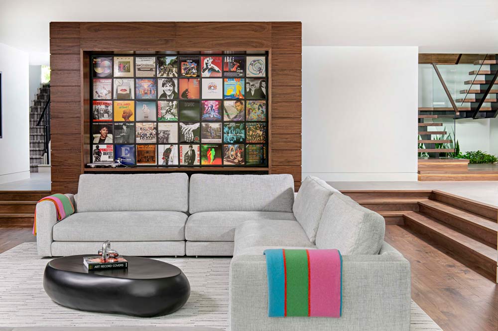 Entertainment area on the lower level with comfortable sofa and a built in feature in the wall above the sofa, displaying record covers surrounded with thick wooden frame