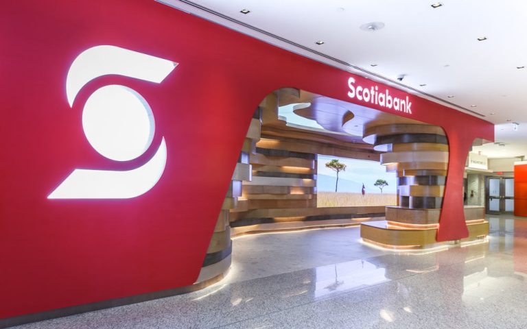 View of the entire Scotiabank North Concourse Lounge, with red framing all around branded wit the logo and inside are the organic occupiable space of undulating wood striations akin to natural cave formations seen in nature