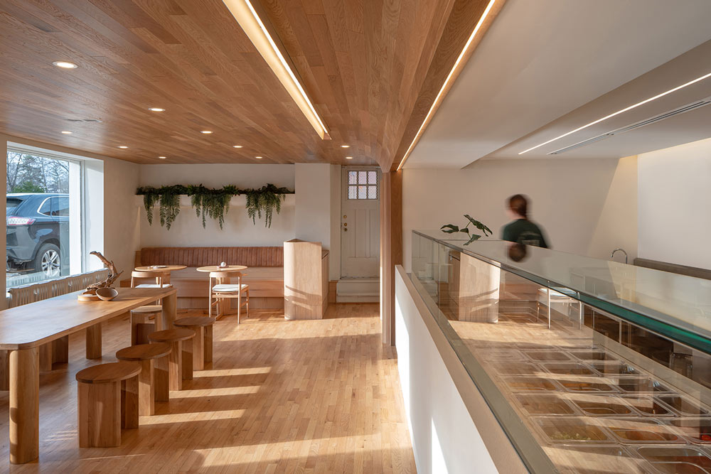 A view of the entire shop looking toward the entrance, with the slaes and display caounter on the right and on the left the large wooden dining table against the large window. 