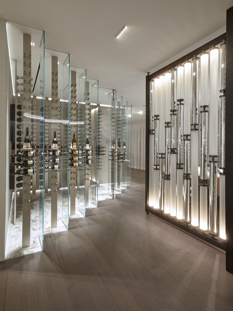 The angular juxtaposition of the glass wine cellar wall is in perfect contrast to the curved, soft lines of the screen made of frosted and mirrored borosilicate tubing. The stepped wall leads from the foyer, through the dining room into the art gallery area,