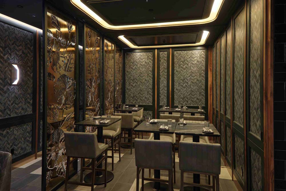 In the dining area the walls are clad with rhymical walnut wood framed panels of shimmering moss green mylar wallcovering