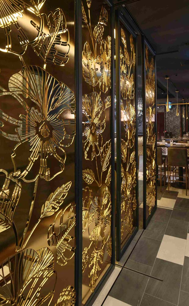 The four panels have gilded large scale, laser cut steel flower cut outs. They also serve the purpose of shielding the corridor leading to the restrooms.