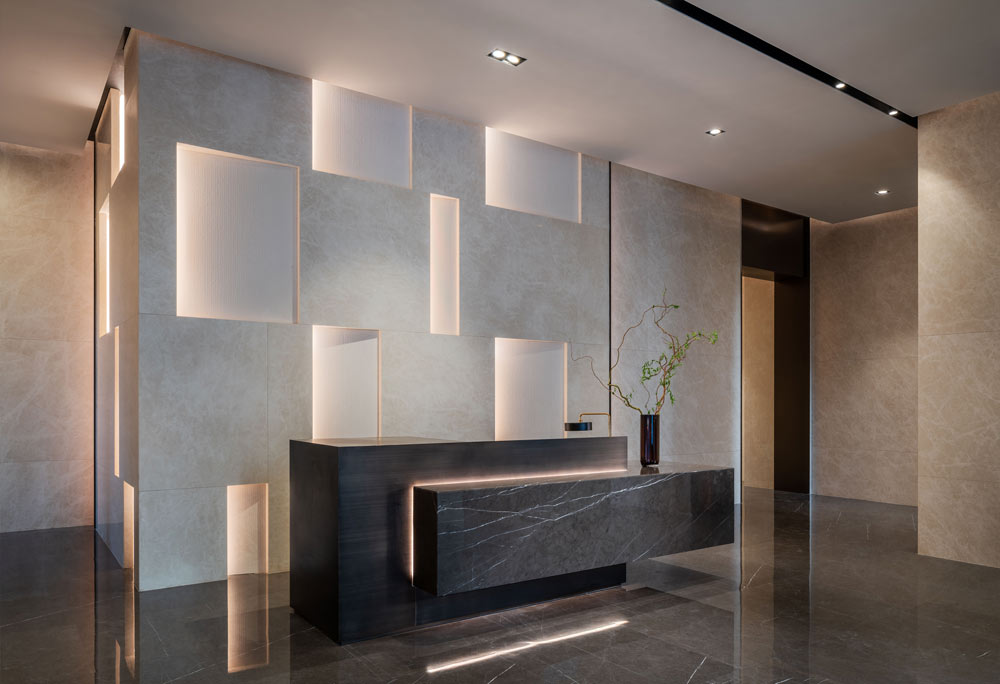 Black modern reception desk in the lobby in contrast to the light coloured wall behind with square and rectangular backlit detailing