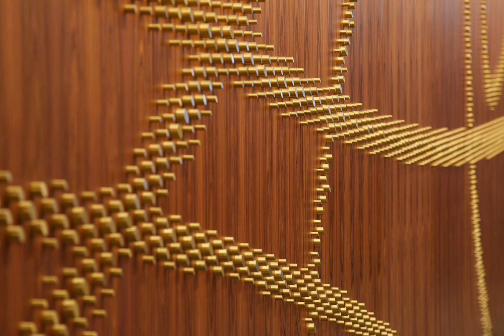 The brass pegs on a wooden panel suggest Braille with which impaired users can interact with