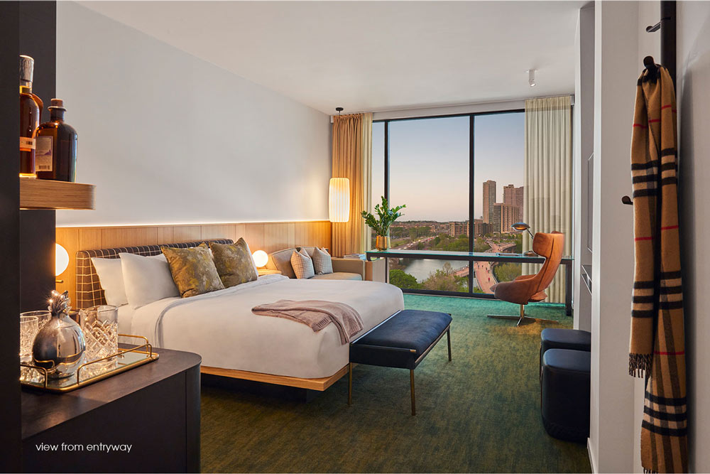 A view of the bedroom with the king size bed in the centre of the room. A view of the city through the wall to ceiling windows
