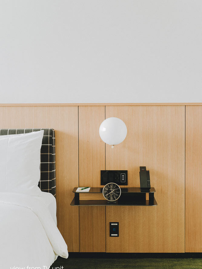 Bed side floating shelf on a wooden panel 'wainscoting' that is mounted across the entire wall behind the bed