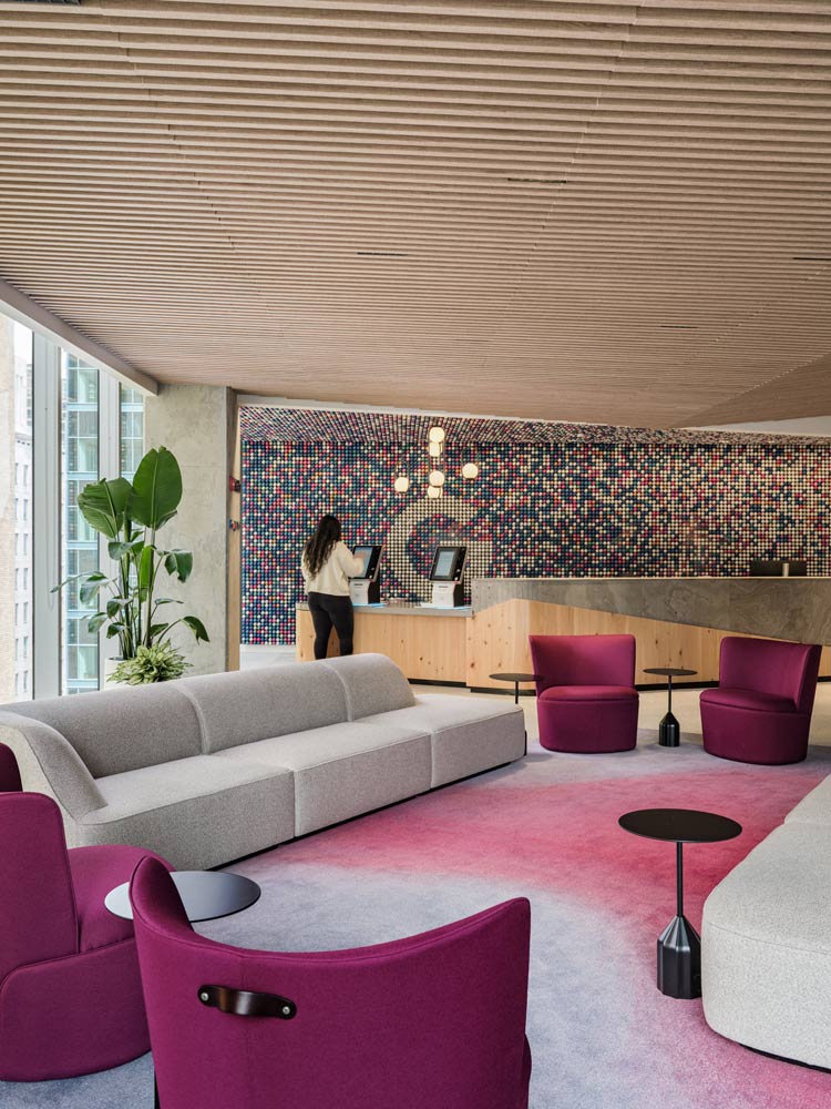 Reception area at 65 King St. East, with magenta and white coloured seating, and a colourful mosaic feature wall behind the reception desk