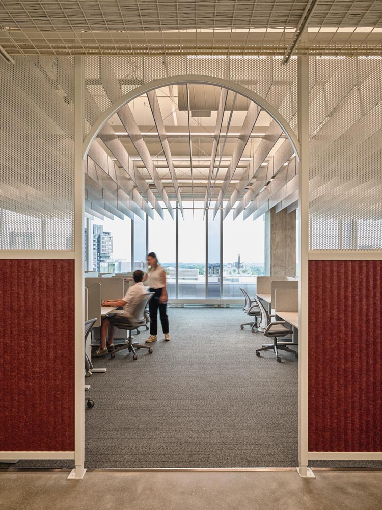 An office space area is visible through an arched door opening. The office looks onto the city through floor to ceiling windows