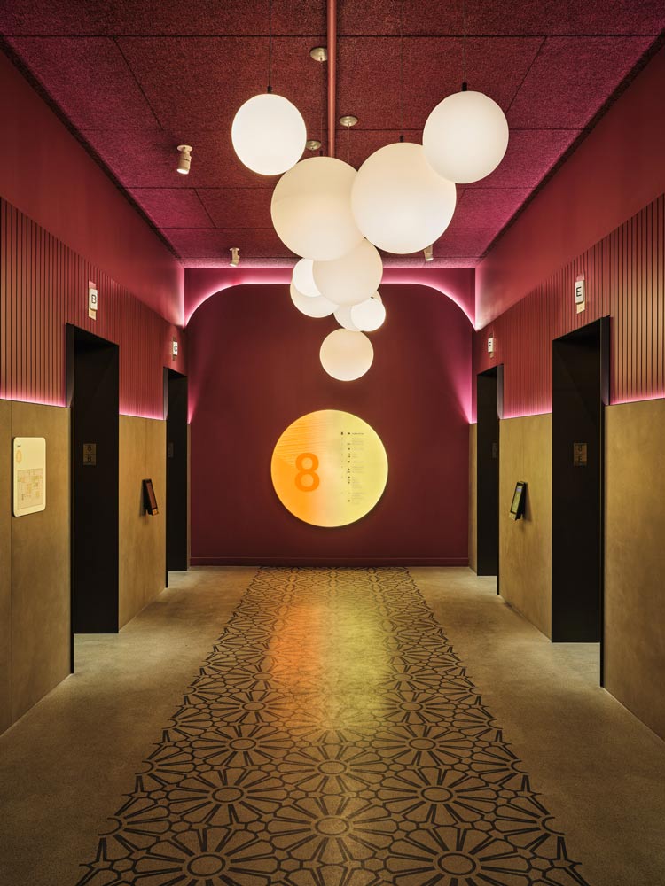 Elevator lobby featuring dark pink walls and ceiling, and large lighting pendant made up of multiple big white spheres