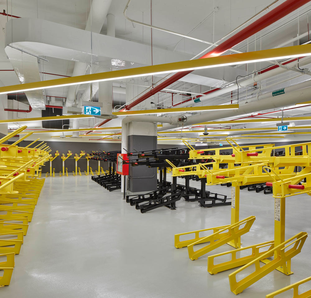 Bike storage room with bright yellow bike holders throughout lined up one next to the other