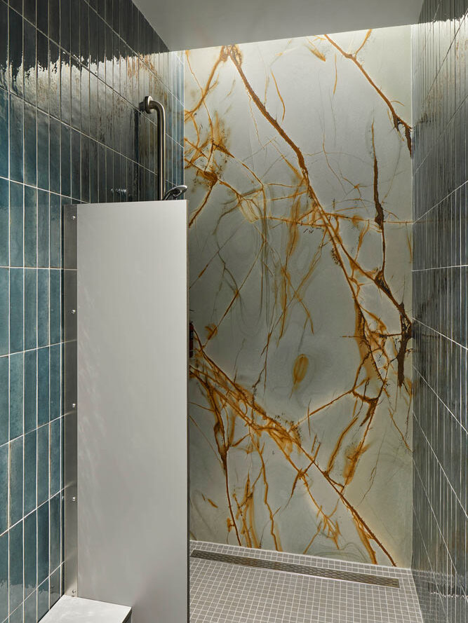 Shower in the changerooms features  teal blue tile and a feature wall in gray with brown marbeling