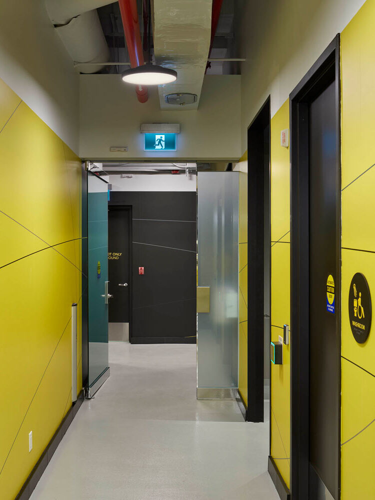 Hallway with bright yellow walls and black doors to accessible washrooms