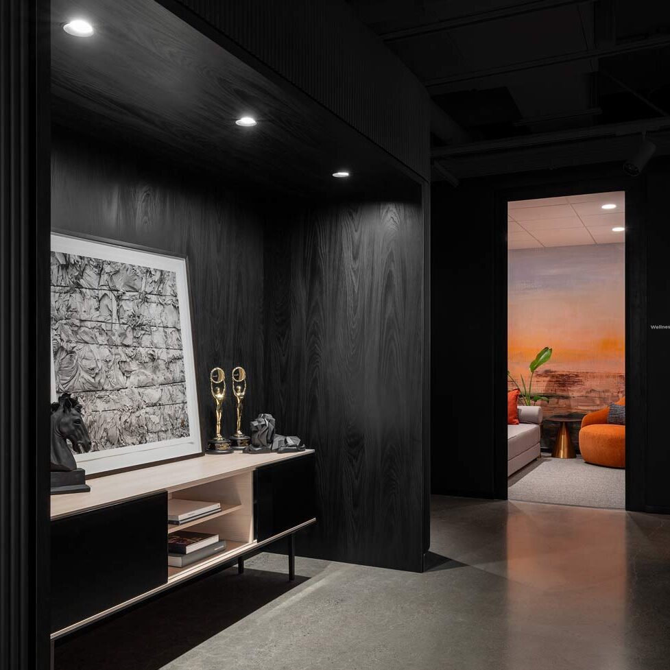 Dark room in black wooden finishes on the walls, leading into a small comfortable and cozy lounge room for relaxation and some private time for employees