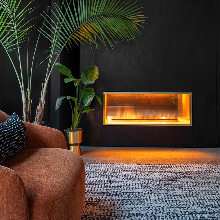 A close up of a built in fire place on a sleek black wall in the lounge room, with a cozy, boutique hotel feel 