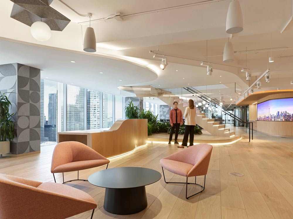 Lounge seating in a wide open area surrounded by floor to ceiling windows on one side. The area features strategic lighting on elements like