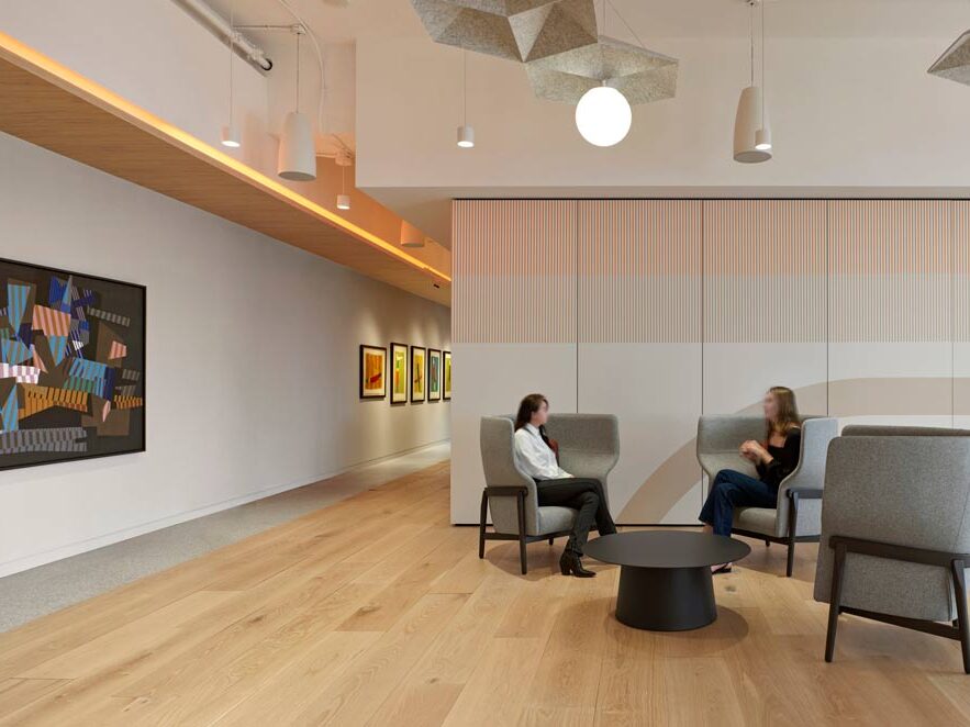 Welcome area with lounge chairs in the centre, and a dramatic art work on the long white wall on the left side