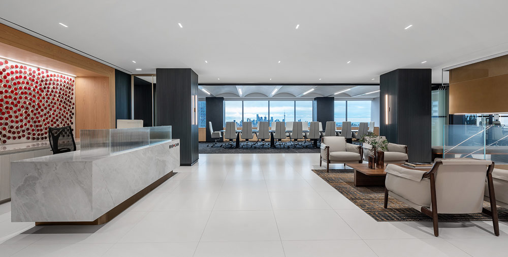 Reception area with the sleek stone reception desk and feature wall behind it on the left and lounge seating on the right, while a long conference table with chairs is visible straight up front