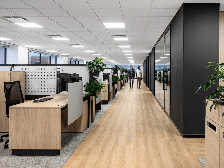Work station area with workstations on the left and offices on the right. All is done in sleek and modern black, white and wooden finishes