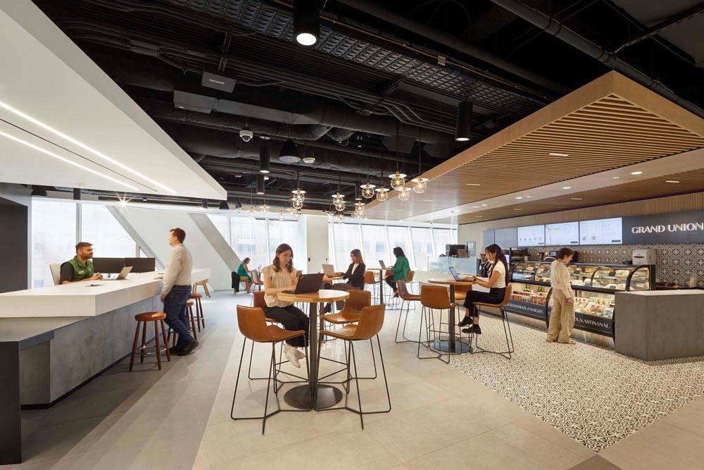 Cafeteria area with industrial elements like high exposed ceilings, wooden details and tables and bar stools in black metal and leather finish