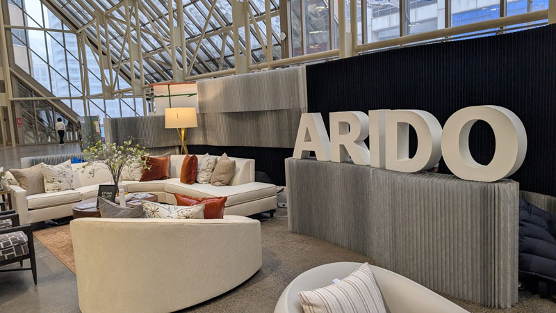 ARIDO letters in the centre of the ARIDO booth at IDS surrounded by lounge furniture