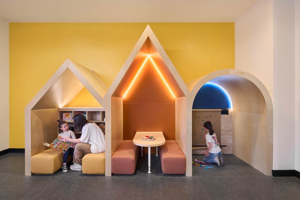 A little play area for kids that looks like 3 attached small play houses each meant for a different activity, reading, drawing and sitting